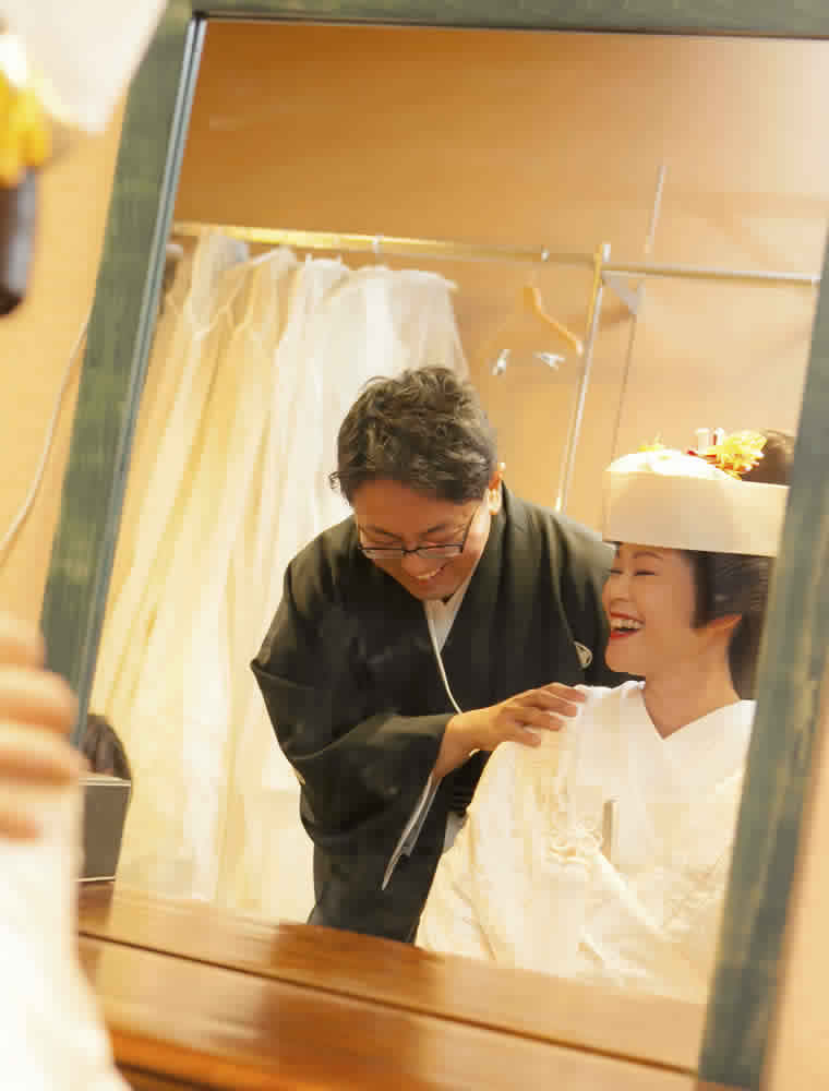 鏡越しで笑い合う婚礼衣装に着替えた新郎新婦