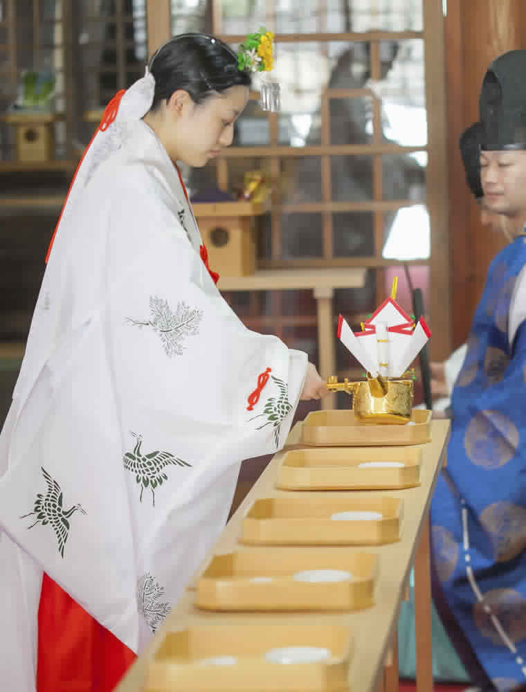 親族固めの杯をするためお神酒を盃に注ぐ巫女