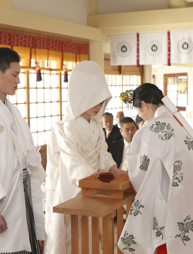 護国神社の巫女からお神酒を受け取る花嫁