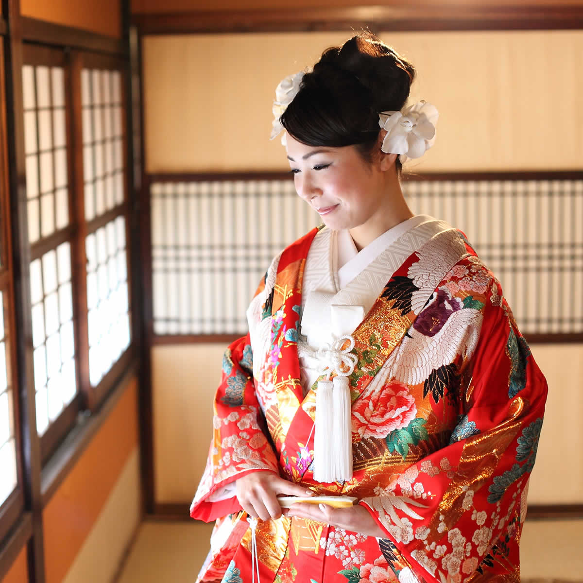 窓際で赤い色打掛を着る花嫁